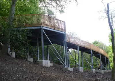 Ancrage d'une passerelle piétone en forêt avec le système d'ancrage Platipus